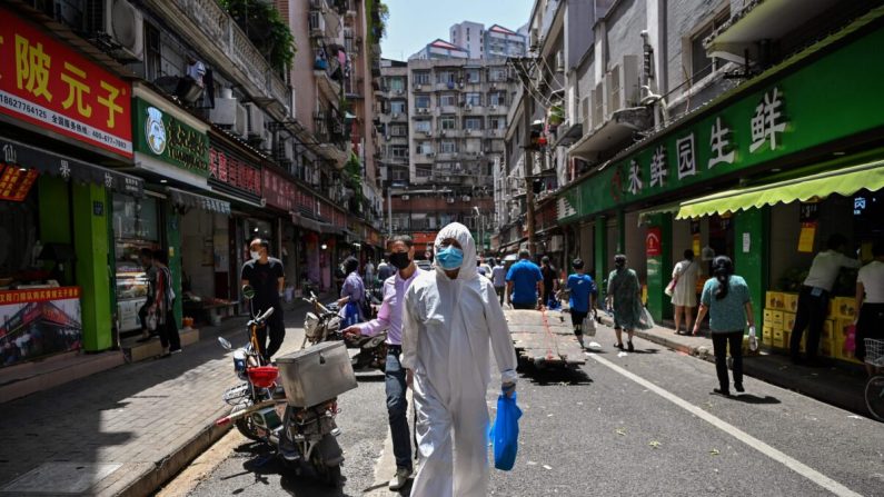 Un homme portant un équipement de protection passe devant des magasins à Wuhan, dans la province chinoise centrale du Hubei, le 18 mai 2020. (Hector Retamal/AFP via Getty Images)