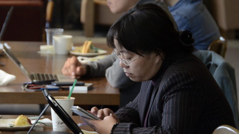 Une femme lit sur son téléphone et sa tablette dans un café à Pékin, en Chine, le 2 novembre 2012. (WANG ZHAO/AFP via Getty Images)