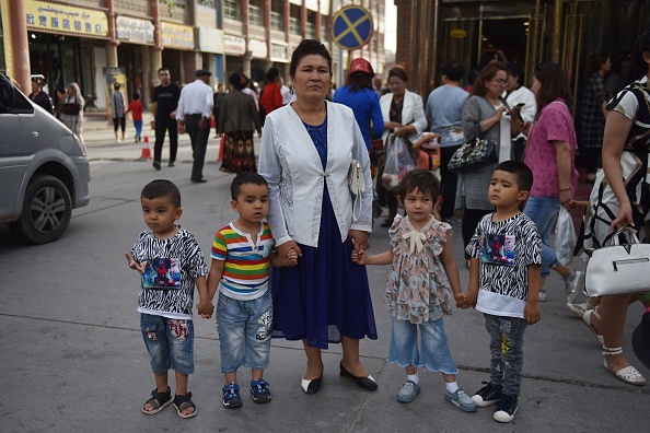 Une Ouïghoure pose avec ses enfants. Ces familles nombreuses sont visées par les autorités chinoises, qui mèneraient une campagne de baisse de la natalité.      (Photo : GREG BAKER/AFP via Getty Images)