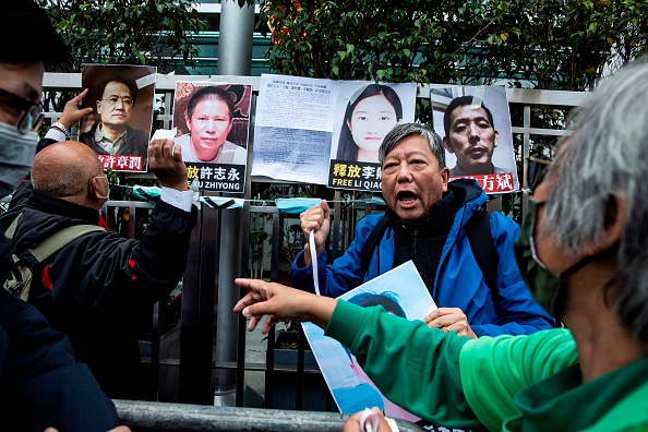 Des manifestants pro-démocratique tiennent des pancartes de militants des droits détenus, à l'extérieur du bureau de liaison chinois à Hong Kong le 19 février 2020, pour protester contre la détention à Pékin de l'éminent militant anti-corruption Xu Zhiyong. Photo par ISAAC LAWRENCE / AFP via Getty Images.
