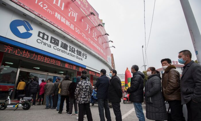 Les clients font la queue pour faire prendre leur température avant d'entrer dans une banque de la ville de Nantong, dans la province de Jiangsu, à l'est de la Chine, le 25 février 2020. (STR/AFP via Getty Images)