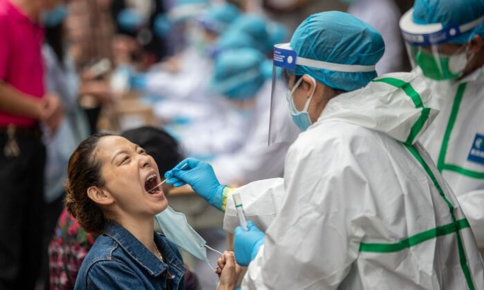 Un soignant prélève un échantillon par écouvillonnage sur une résidente pour le soumettre au test de dépistage du virus du PCC à Wuhan, en Chine, le 15 mai 2020. (STR/AFP via Getty Images)