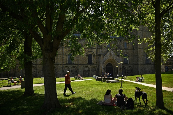 -Illustration- Des gens sont assis sur l'herbe à l'extérieur de la cathédrale de Durham, dans le nord-est de l'Angleterre. Photo par Oli SCARFF / AFP via Getty Images.