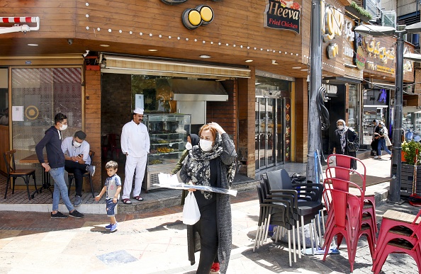 -Des Iraniens passent devant un restaurant de la capitale, Téhéran, le 26 mai 2020. L'Iran, le 25 mai, a rouvert les principaux sanctuaires chiites de toute la République islamique, plus de deux mois après leur fermeture. Cependant le coronavirus est loin d’être terminé, un nouveau pic semble s’annoncer. Photo par - / AFP via Getty Images.