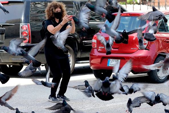 -La réalisatrice libanaise Carol Mansour utilise son téléphone pour filmer des pigeons volant tout en portant un masque facial, dans le centre de la capitale Beyrouth, le 1er juin 2020.  Photo de JOSEPH EID / AFP via Getty Images.