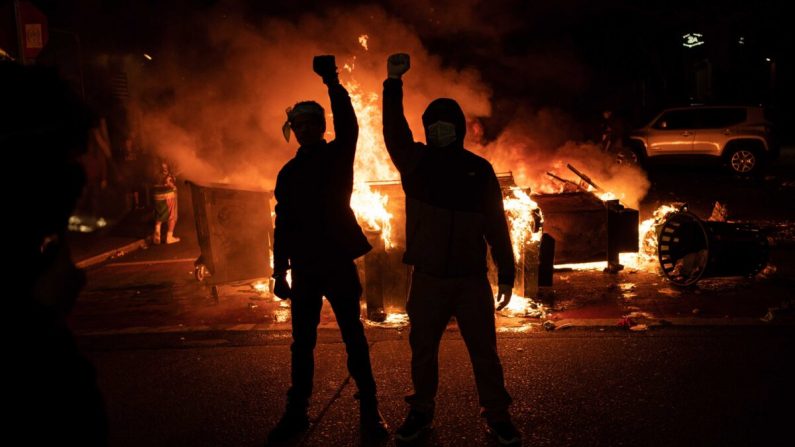 Des manifestants lèvent le poing alors qu'un incendie brûle dans la rue après des affrontements avec les forces de l'ordre, près  du département de police dans le quartier Est, à Seattle (Washington), le 8 juin 2020. (David Ryder/Getty Images)
