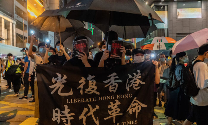 Des manifestants tiennent une banderole alors qu'ils défilent dans une rue lors d'un rassemblement dans le district central de Hong Kong le 9 juin 2020. (Anthony Kwan/Getty Images)