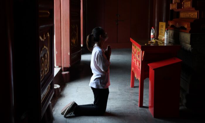 Une femme portant un masque prie au temple des Lama à Pékin, en Chine, après sa réouverture le 10 juin 2020. (GREG BAKER/AFP via Getty Images)