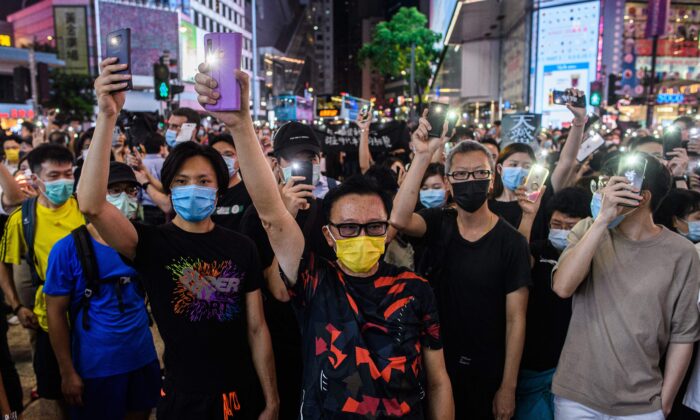 Des militants pro-démocratie brandissent leur lampe torche de téléphone portable alors qu'ils chantent lors d'un rassemblement dans le quartier de Causeway Bay à Hong Kong le 12 juin 2020. (Anthony Wallace/AFP via Getty Images)