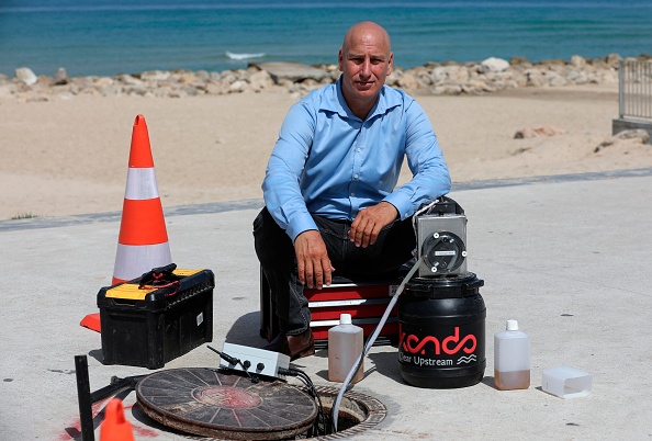 -Ari Goldfarb, fondateur et PDG de la société israélienne Kando, pose à côté d'un trou d'homme utilisé pour analyser des échantillons d'eaux usées, près de la plage dans la ville côtière du sud d'Israël à Ashkelon, le 11 juin 2020. Photo par MENAHEM KAHANA / AFP via Getty Images.