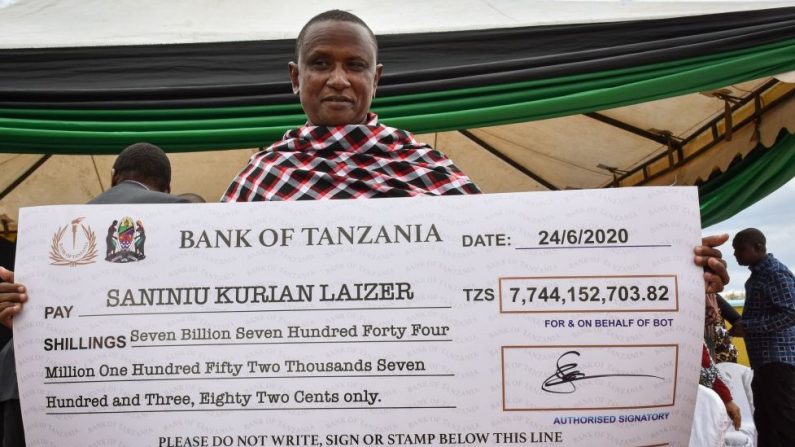 Le mineur artisanal tanzanien Saniniu Kuryan Laizer, 52 ans, pose avec la copie agrandie du chèque du gouvernement après avoir vendu deux des plus grosses pierres précieuses du pays, la tanzanite, le 24 juin 2020. (Photo by FILBERT RWEYEMAMU/AFP via Getty Images)