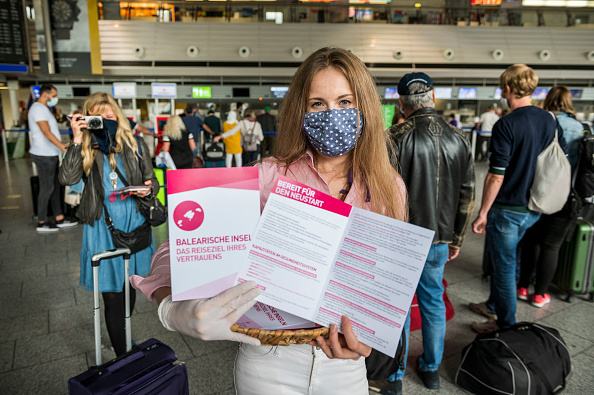 -Les touristes montrent leur carte d'embarquement après l'enregistrement pour un vol TUIfly à Majorque à l'aéroport de Francfort le premier jour que les voyages à forfait reprennent depuis mars pendant la pandémie de coronavirus
