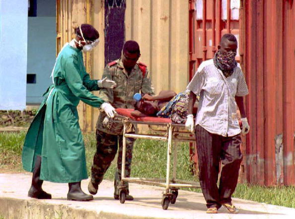 Un soldat zaïrois, un civil et un médecin  transportent un patient atteint du virus mortel Ebola à l'hôpital de la ville de Kikwit, à 320 miles au sud-est de la capitale zaïroise Kinshasa. Le 14 mai 2020. (Photo : CHRISTOPHE SIMON/AFP via Getty Images)