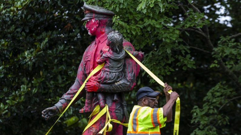 Des travailleurs enlèvent une statue commémorative de la police couverte de peinture rouge par des manifestants à Richmond, en Virginie, le 11 juin 2020. (Zach Gibson/Getty Images)