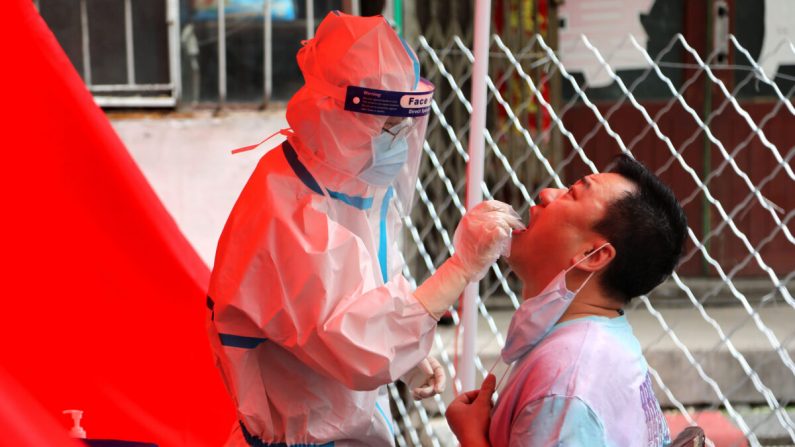 Un professionnel de la santé prélève un échantillon par écouvillonnage sur un habitant pour le soumettre à un test de dépistage du virus du PCC dans une rue de Mudanjiang, en Chine, le 3 juin 2020. (STR/AFP via Getty Images)