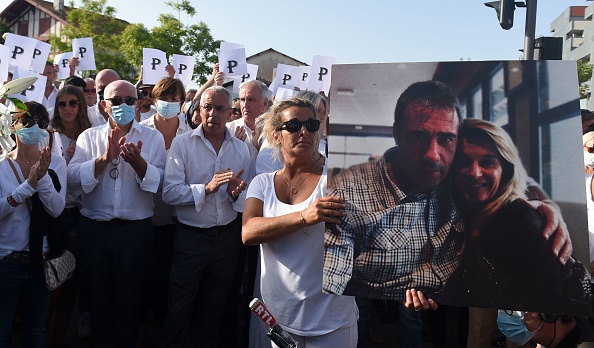 Véronique Monguillot, l’épouse du conducteur de bus sauvagement agressé le dimanche 5 juillet, tient à bout de bras une photo de son mari pendant la marche blanche organisée à Bayonne le 8 juillet. Crédit : GAIZKA IROZ/AFP via Getty Images.