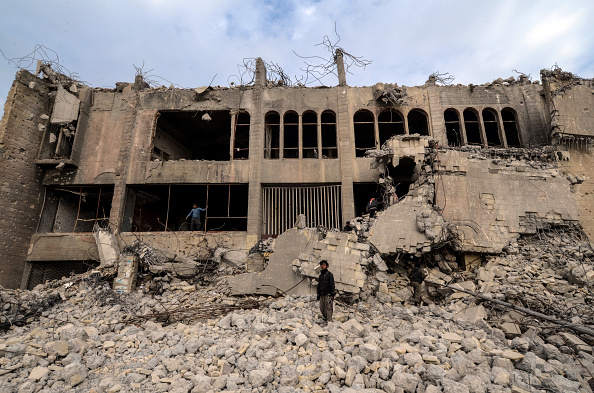 -Un Irakien se tient sur les décombres du bâtiment Chadirji de sept étages détruit, conçu par le célèbre architecte irakien Rifat Chadirji dans les années 1960, le 13 janvier 2019, dans la ville de Mossoul. Photo de Zaid AL-OBEIDI / AFP via Getty Images.