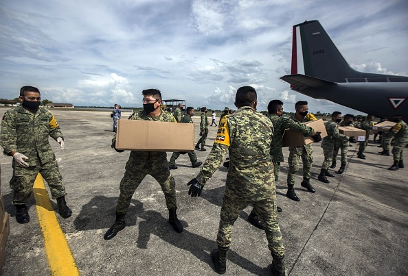 -Des membres de l'armée mexicaine déchargent depuis un avion des boîtes contenant des fournitures et des équipements médicaux, pour les hôpitaux où des patients atteints de COVID-19 sont traités, le 22 mai 2020. Photo par HUGO BORGES / AFP via Getty Images.