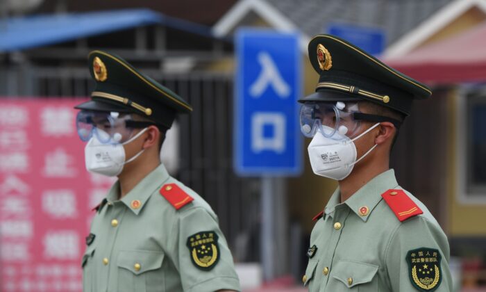 Des agents de la police paramilitaire portent des masques et des lunettes de protection alors qu'ils montent la garde à l'entrée du marché fermé de Xinfadi à Pékin, le 13 juin 2020. (GREG BAKER/AFP via Getty Images)