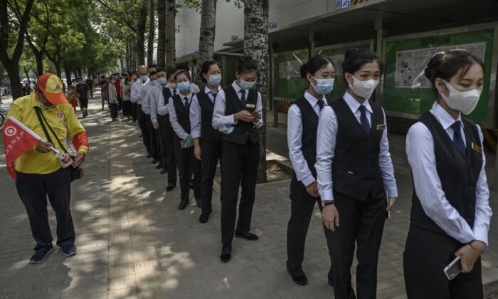 Des travailleurs de l'industrie des services chinoise font la queue pour des tests d'acide nucléique par écouvillonnage pour dépister le Covid-19 sur un site d'essai à Pékin le 1er juillet 2020. (Kevin Frayer/Getty Images)