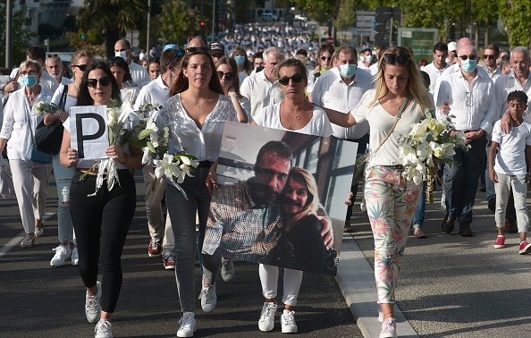 Portant une grande photo d'elle et de son mari enlacés, Véronique Monguillot (c) a marché en tête du défilé avec ses filles - Marie, 18 ans, Manon, 21 ans et Mélanie, 24 ans, chacune avec un bouquet de fleurs blanches en mains. (Photo by IROZ GAIZKA/AFP via Getty Images)