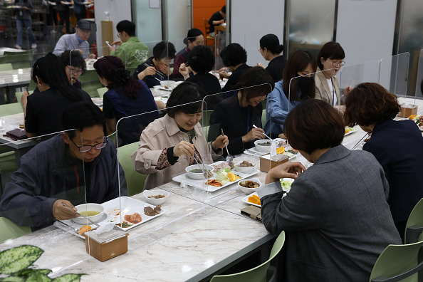 -Illustration- Les gens déjeunent derrière des barrières de protection en plastique sur la table entre les convives, les Sud-Coréens prennent des mesures pour se protéger contre la propagation du coronavirus. Photo Chung Sung-Jun/Getty Images.