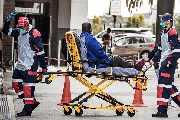 -Un ambulancier paramédical d'urgence porte un équipement de protection et fait le signe de la victoire à son arrivée à l'hôpital Greenacres de Port Elizabeth, le 10 juillet 2020. Photo de MARCO LONGARI / AFP via Getty Images.