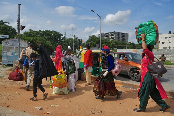 Une famille transportant ses effets personnels cherche un moyen de transport pour retourner dans sa ville natale à la frontière de l'État du Karnataka-Tamil Nadu à la périphérie de Bangalore le 13 juillet 2020, alors qu'un nouveau reconfinement est en cours à Bangalore, en Inde. (Photo : MANJUNATH KIRAN/AFP via Getty Images)