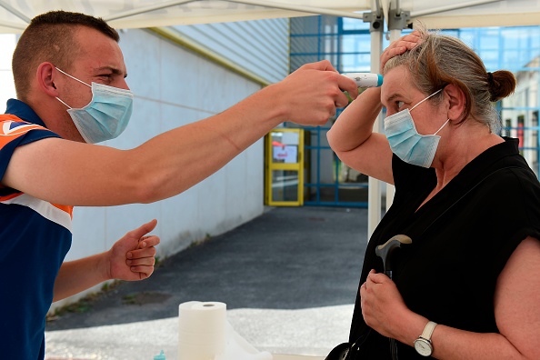 -Un sauveteur de la protection civile prend la température d'une femme avant de subir un test COVID-19, à Laval, dans l'ouest de la France, le 17 juillet 2020. Photo par JEAN-FRANCOIS MONIER / AFP via Getty Images.