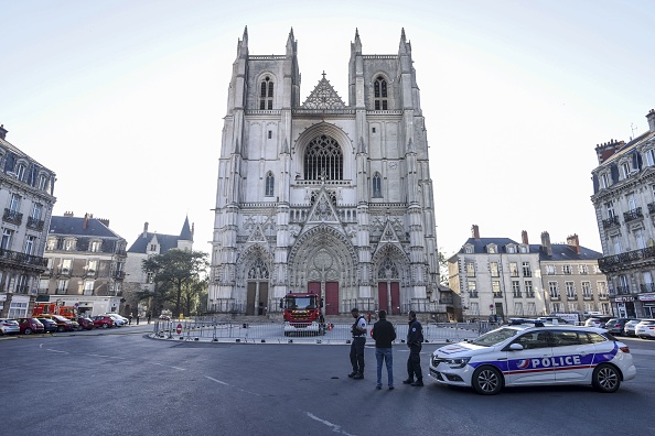 -Des policiers français regardent la façade partiellement brûlée de la cathédrale Saint-Pierre-et-Saint-Paul de Nantes, dans l'ouest de la France, le 19 juillet 2020. Photo par SEBASTIEN SALOM-GOMIS / AFP via Getty Images.