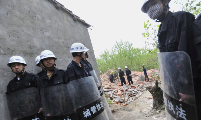 Des agents de sécurité chinois portent des bâtons alors qu'ils montent la garde pendant que des ouvriers démolissent des maisons à Wuhan, dans la province de Hubei, en Chine centrale, le 7 mai 2010. (AFP/AFP via Getty Images)