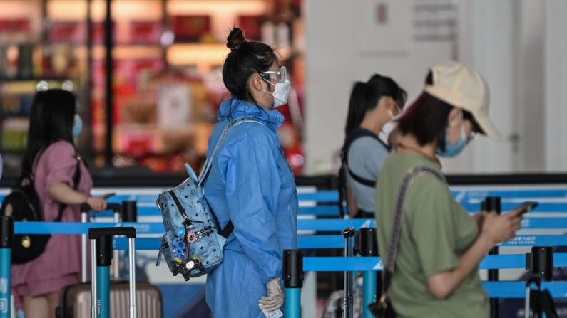 Un passager qui porte un équipement de protection et un masque fait la queue au comptoir d'une compagnie aérienne à l'aéroport de Tianhe à Wuhan, dans la province de Hubei en Chine centrale, le 23 mai 2020. (Hector Retamal/AFP via Getty Images)