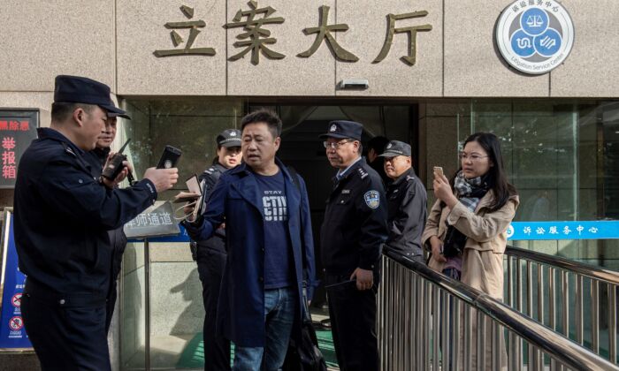 L'avocat Xie Yang (au centre) accompagné de son client Xu Yan (à droite), l'épouse de l'avocat des droits de l'homme Yu Wensheng, tentent de rencontrer Yu Wensheng en personne devant le tribunal intermédiaire de Xuzhou, à Xuzhou, dans la province du Jiangsu, à l'est de la Chine, le 31 octobre 2019. (NICOLAS ASFOURI/AFP via Getty Images)