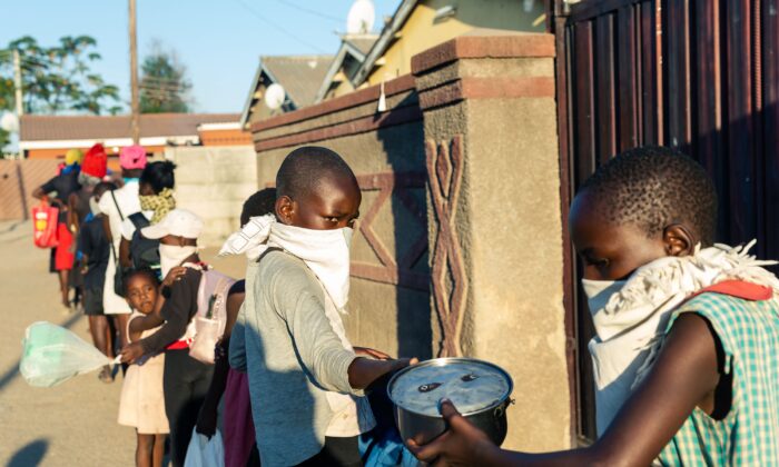 Les gens font la queue pour un repas gratuit pendant la période de confinement imposé par le gouvernement à Chitungwiza, au Zimbabwe, le 5 mai 2020. (JEKESAI NJIKIZANA/AFP via Getty Images)