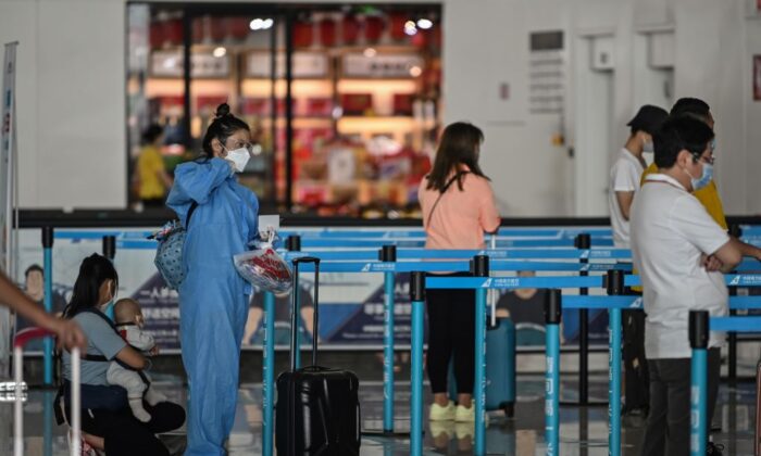 Un passager portant un équipement de protection et un masque fait la queue au comptoir d'une compagnie aérienne, à l'aéroport de Tianhe à Wuhan, dans la province de Hubei, en Chine centrale, le 23 mai 2020. (Hector Retamal/AFP via Getty Images)