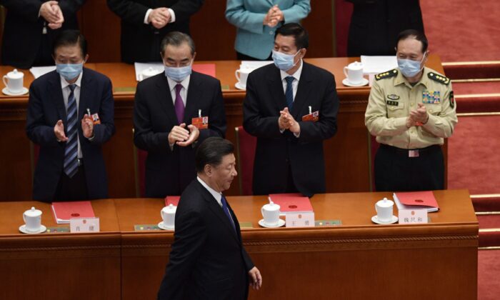 Le leader chinois Xi Jinping est applaudi par les hauts fonctionnaires alors qu'il arrive pour la session de clôture de la conférence législative du régime, qui se tient dans le Grand Hall du peuple à Pékin, le 28 mai 2020. (NICOLAS ASFOURI/AFP via Getty Images)