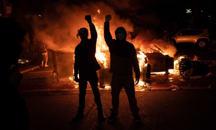 Des manifestants lèvent le poing sur un fond d’incendie après leurs affrontements avec les forces de l'ordre à Seattle, États-Unis, le 8 juin 2020. (David Ryder/Getty Images)