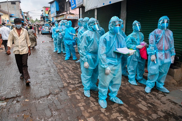 -Le personnel médical ainsi que les volontaires attendent pour commencer un examen médical porte-à-porte dans un bidonville pour lutter contre la propagation du coronavirus. Photo par INDRANIL MUKHERJEE / AFP via Getty Images.