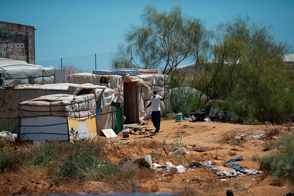 -Un saisonnier se tient devant un bidonville de Lepe, près de Huelva, le 29 juillet 2020. - Photo par CRISTINA QUICLER / AFP via Getty Images.