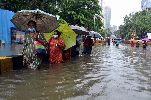 -Les gens pataugent dans l'eau jusqu'aux genoux le long d'une route inondée lors d'une forte pluie de mousson à Mumbai le 4 août 2020. Photo de Sujit Jaiswal / AFP via Getty Images.