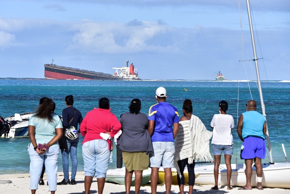 -Des spectateurs regardent le vraquier MV Wakashio qui s'était échoué et dont le pétrole fuit près du parc marin de Blue Bay dans le sud-est de l'île Maurice le 6 août 2020. Photo  Dev RAMKHELAWON / L'Express Maurice / AFP via Getty Images.