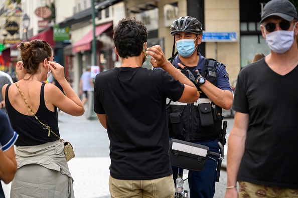 -Un agent de la police municipale de Paris portant un masque facial demande aux gens de mettre leur masque dans la rue Montorgueil à Paris, le 15 août 2020. Photo par BERTRAND GUAY / AFP via Getty Images.