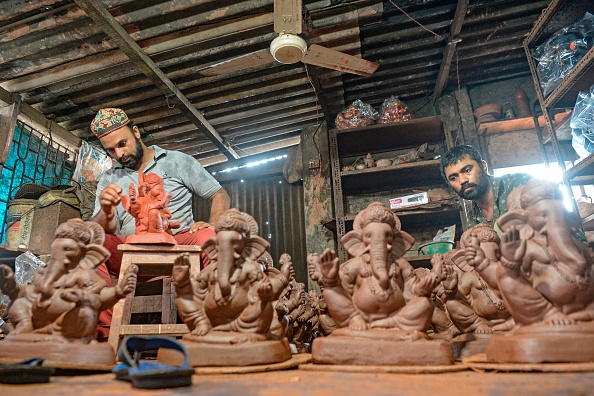Le potier musulman Yusuf Zakaria Galwani avec son personnel, travaille sur les idoles du dieu hindou à tête d'éléphant Ganesha dans son atelier à Kumbharwada dans les bidonvilles de Dharavi à Mumbai. Photo par INDRANIL MUKHERJEE / AFP via Getty Images.