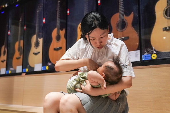 -Madame Wang Chao nourrit son enfant dans son magasin de guitares à Shanghai, le 5 août 2020. Photo par STR / AFP via Getty Images.