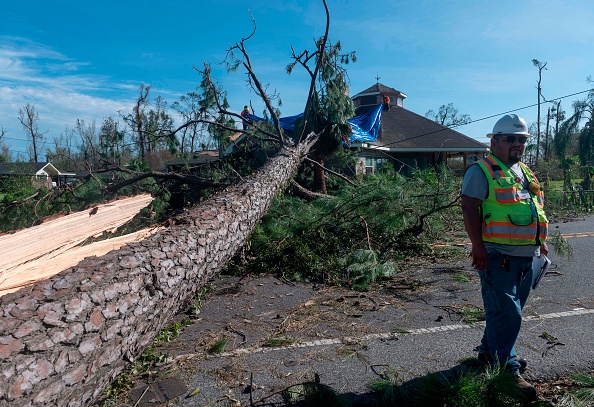 -Un employé d'une entreprise d'électricité surveille les dommages causés aux lignes électriques à côté d'un grand arbre tombé sur une maison à la suite du passage de l'ouragan Laura à Lake Charles le 27 août 2020. - Photo par ANDREW CABALLERO-REYNOLDS / AFP via Getty Images.