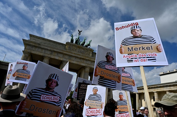 -Des pancartes représentant la chancelière allemande Angela Merkel et des ministres en tant que prisonniers sont vues lors d'une manifestation appelée pour protester contre les restrictions liées à la nouvelle pandémie de coronavirus, le 29 août 2020 à Berlin. Photo de JOHN MACDOUGALL / AFP via Getty Images.