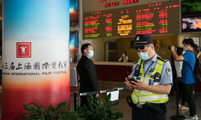 Un policier regarde son téléphone portable au Shanghai Film Center (SFC) à Shanghai le 25 juillet 2020. (Yifan Ding/Getty Images)