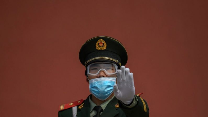 Un officier de police paramilitaire chinois fait de geste alors qu'il porte un masque de protection en montant la garde à l'entrée de la Cité interdite lors de sa réouverture à un nombre limité de visiteurs à Pékin, en Chine, le 1er mai 2020. (Kevin Frayer/Getty Images)