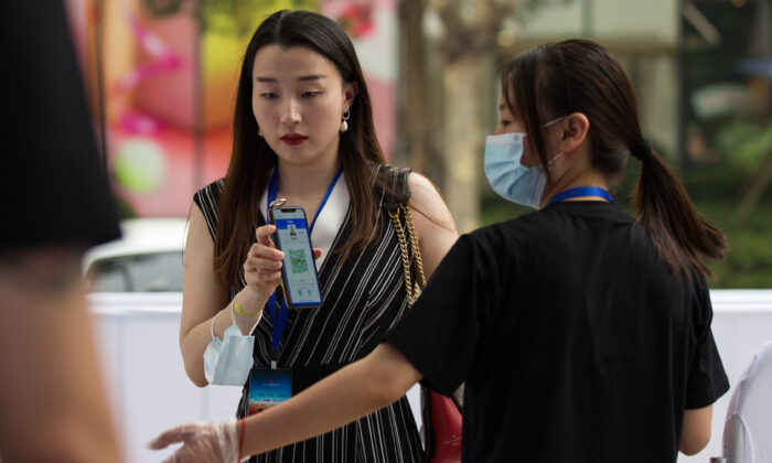 Un membre du personnel porte un masque de protection lorsqu'il vérifie le code QR d'une spectatrice à l'entrée, avant une projection en plein air à Shanghai, en Chine, le 25 juillet 2020. (Yifan Ding/Getty Images)