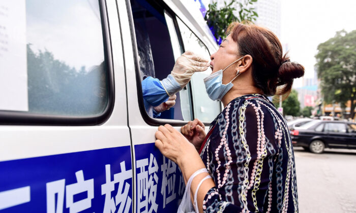 Un soignant effectue un test Covid-19 sur un résident dans un véhicule de test à Shenyang, dans la province du Liaoning au nord-est de la Chine, le 29 juillet 2020. (STR/AFP via Getty Images)